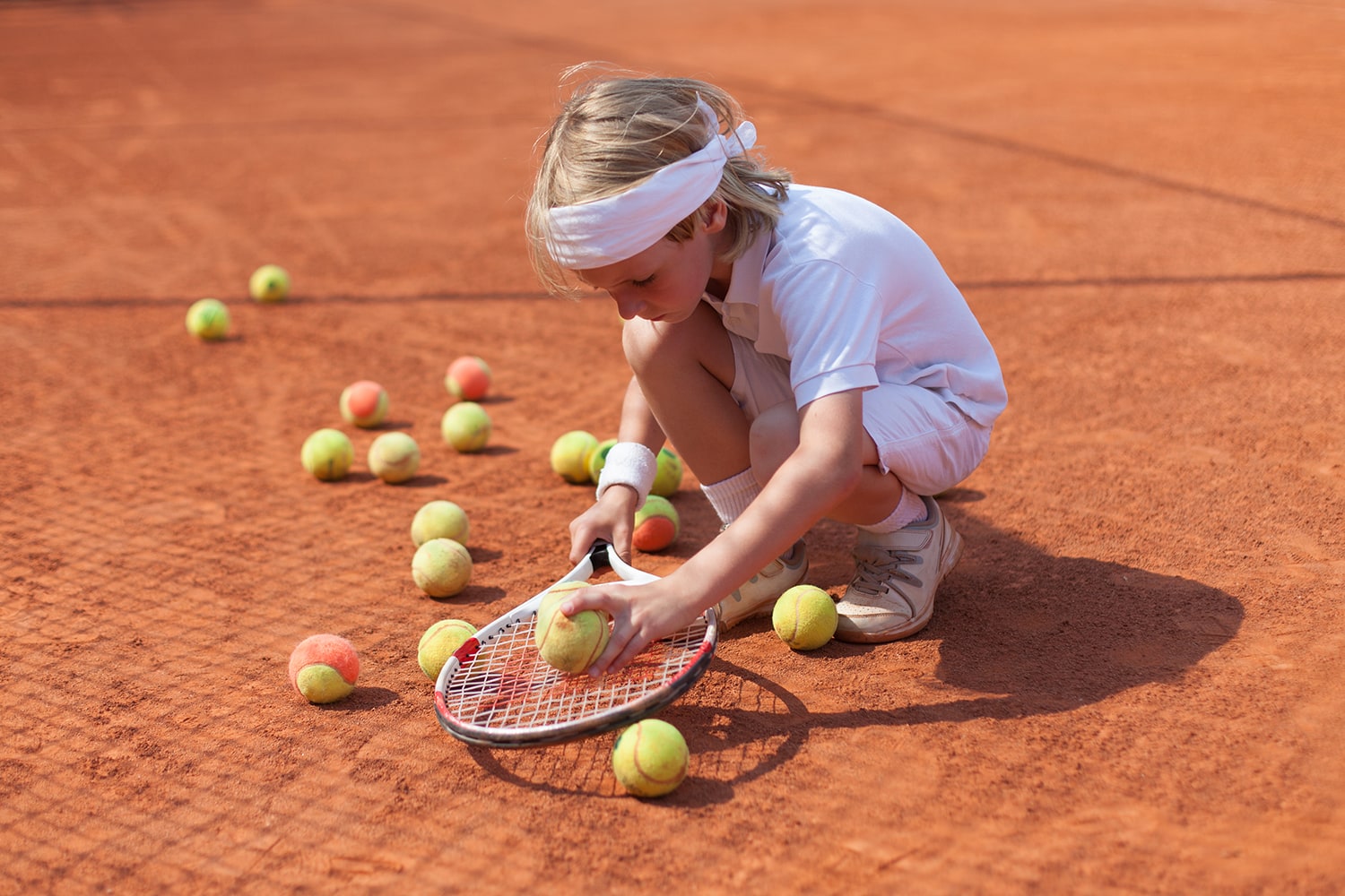 Junge sammelt Tennisbälle ein